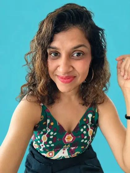 Nikita Joshi, smiling, with curly hair.